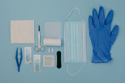 Flat lay of essential first aid items including gloves, mask, and scissors on a light background.
