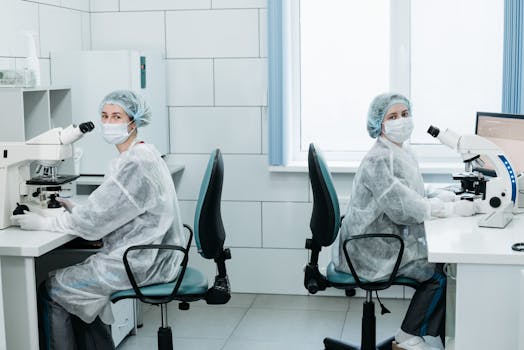 Two female scientists working with microscopes in a laboratory setting.